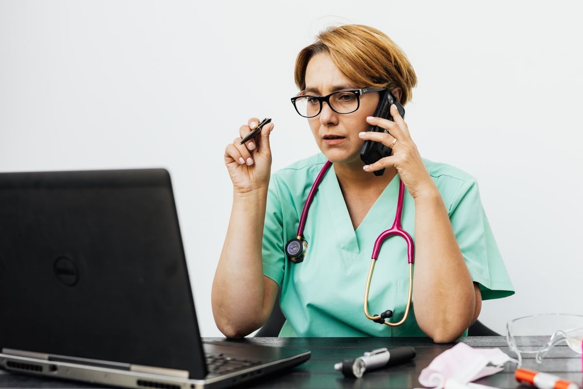 Médica usando laptop no consultório com estetoscópio - IA para médicos