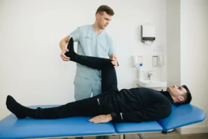 Fisioterapeuta auxilia paciente durante exercício de alongamento em uma maca